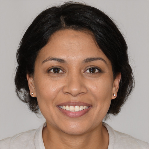 Joyful latino adult female with medium  brown hair and brown eyes