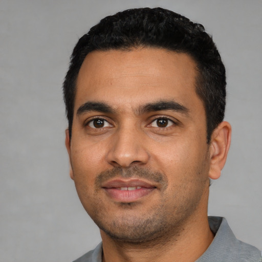 Joyful latino young-adult male with short  black hair and brown eyes