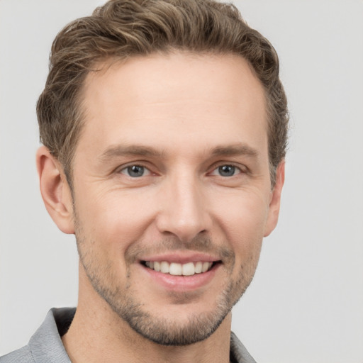 Joyful white young-adult male with short  brown hair and grey eyes