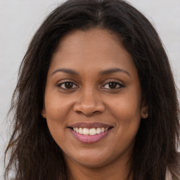 Joyful black young-adult female with long  brown hair and brown eyes