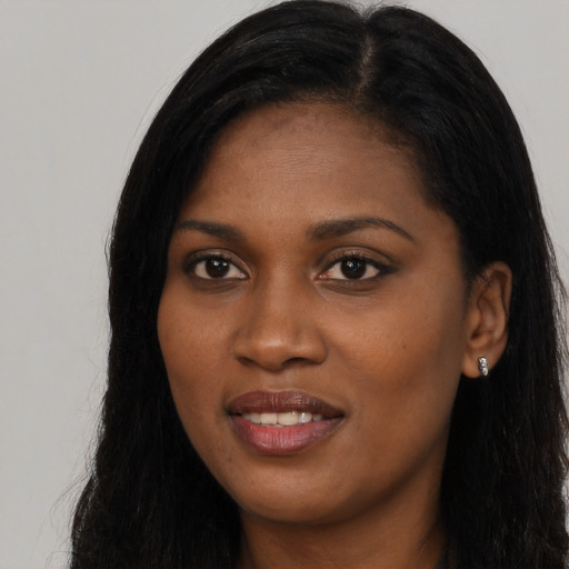 Joyful black young-adult female with long  black hair and brown eyes