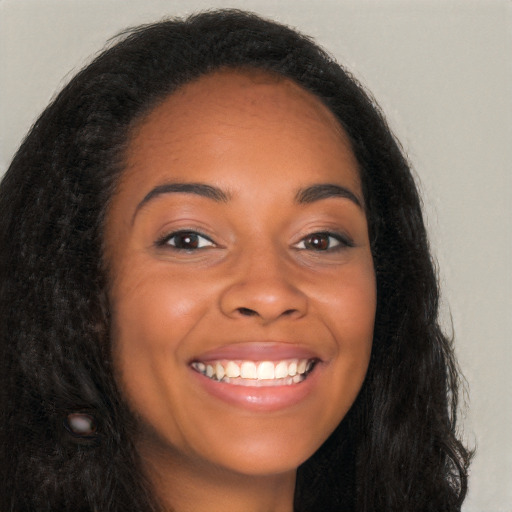 Joyful black young-adult female with long  brown hair and brown eyes