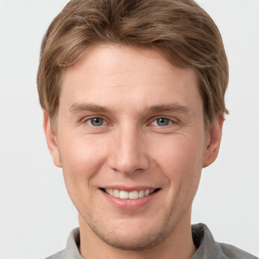 Joyful white young-adult male with short  brown hair and grey eyes