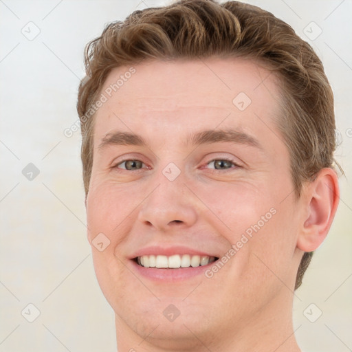 Joyful white young-adult male with short  brown hair and grey eyes