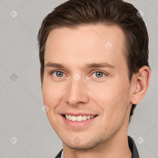 Joyful white young-adult male with short  brown hair and grey eyes