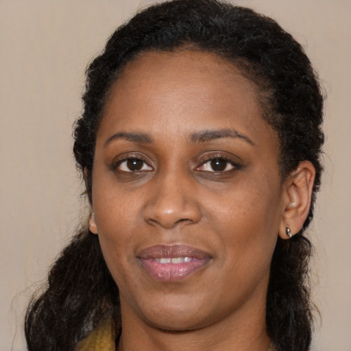 Joyful black young-adult female with long  brown hair and brown eyes