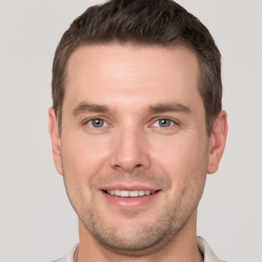 Joyful white young-adult male with short  brown hair and grey eyes