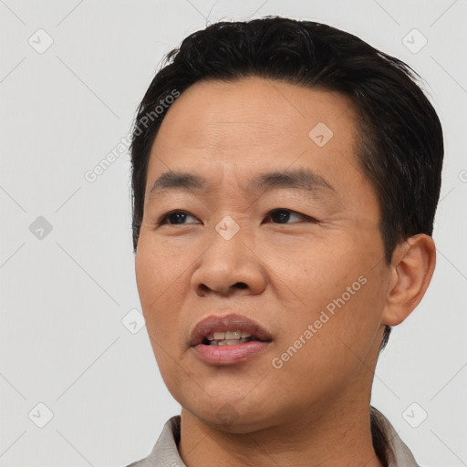 Joyful asian adult male with short  black hair and brown eyes