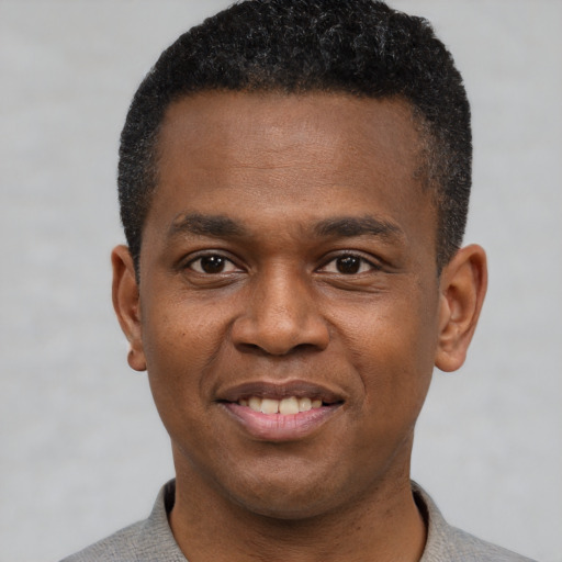 Joyful black young-adult male with short  black hair and brown eyes