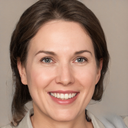 Joyful white adult female with medium  brown hair and grey eyes