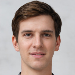 Joyful white young-adult male with short  brown hair and grey eyes