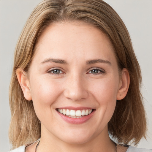 Joyful white young-adult female with medium  brown hair and grey eyes