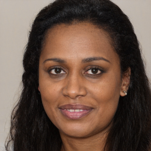Joyful black young-adult female with long  brown hair and brown eyes