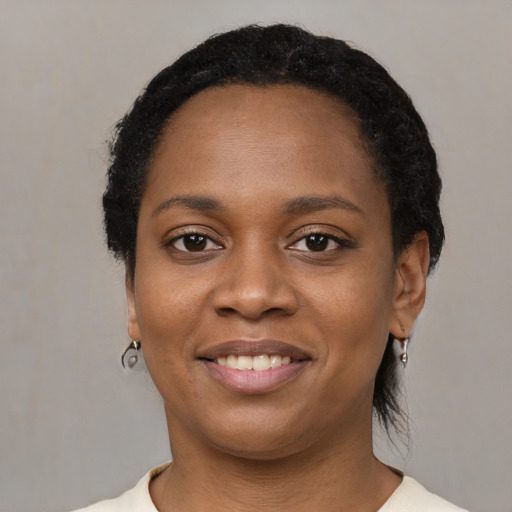 Joyful black young-adult female with short  black hair and brown eyes