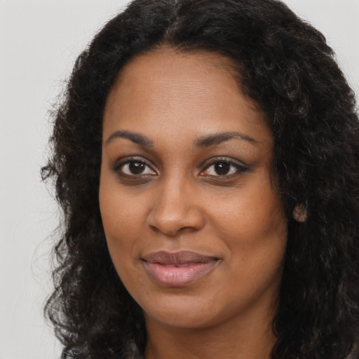 Joyful black young-adult female with long  brown hair and brown eyes
