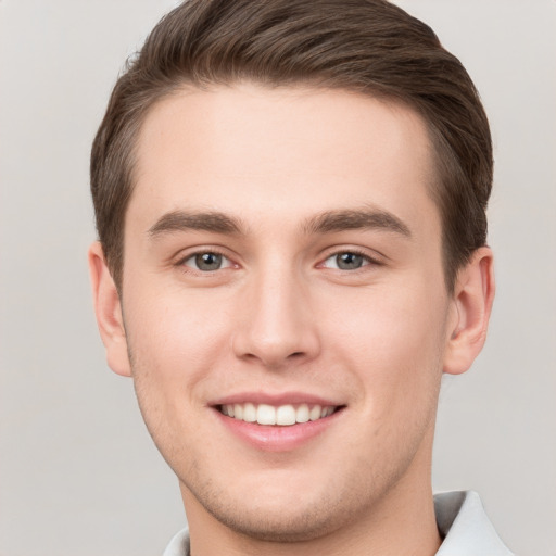 Joyful white young-adult male with short  brown hair and grey eyes