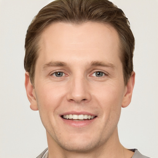 Joyful white young-adult male with short  brown hair and grey eyes