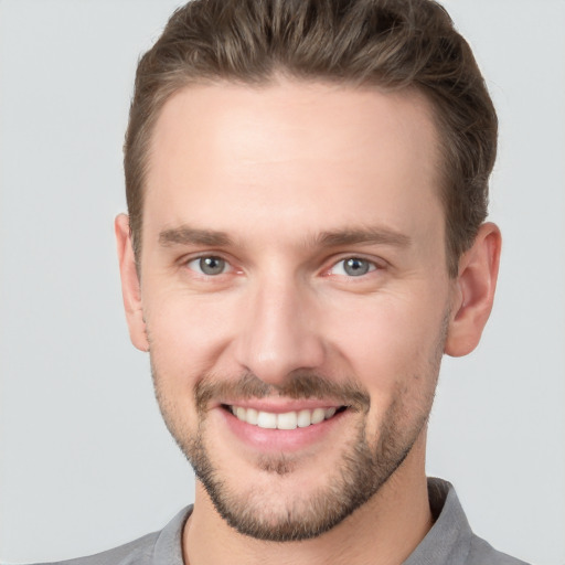 Joyful white young-adult male with short  brown hair and grey eyes