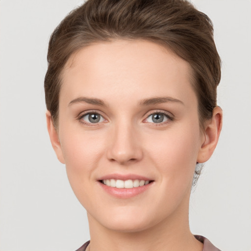 Joyful white young-adult female with short  brown hair and grey eyes