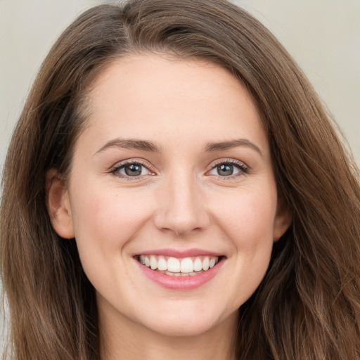 Joyful white young-adult female with long  brown hair and grey eyes