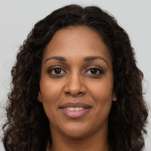 Joyful black young-adult female with long  brown hair and brown eyes