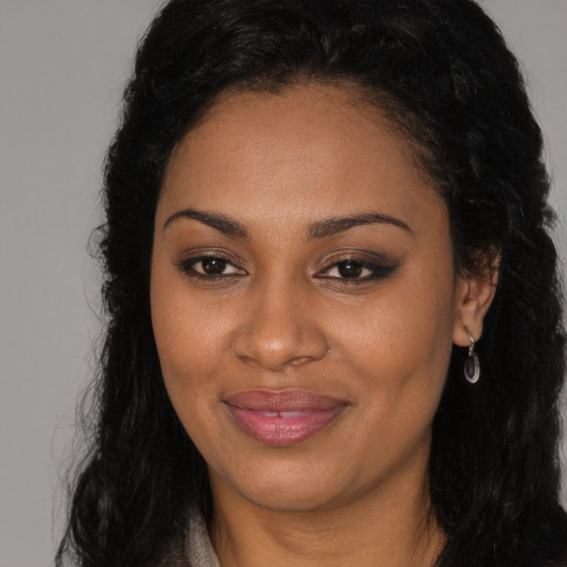 Joyful black young-adult female with long  brown hair and brown eyes