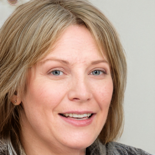 Joyful white adult female with medium  brown hair and blue eyes