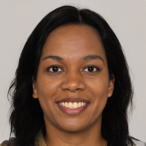 Joyful black young-adult female with long  black hair and brown eyes