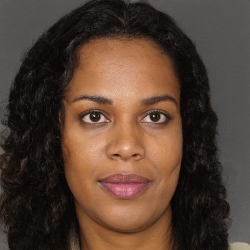 Joyful black young-adult female with long  brown hair and brown eyes