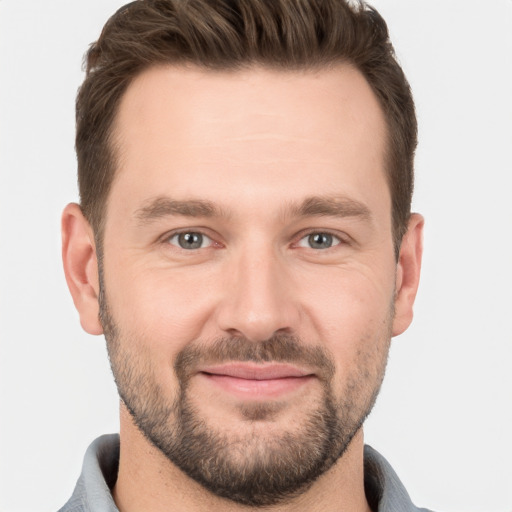 Joyful white young-adult male with short  brown hair and grey eyes