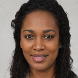 Joyful black young-adult female with long  brown hair and brown eyes