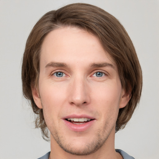 Joyful white young-adult male with medium  brown hair and grey eyes