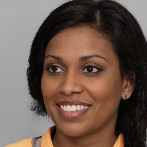 Joyful black young-adult female with long  black hair and brown eyes