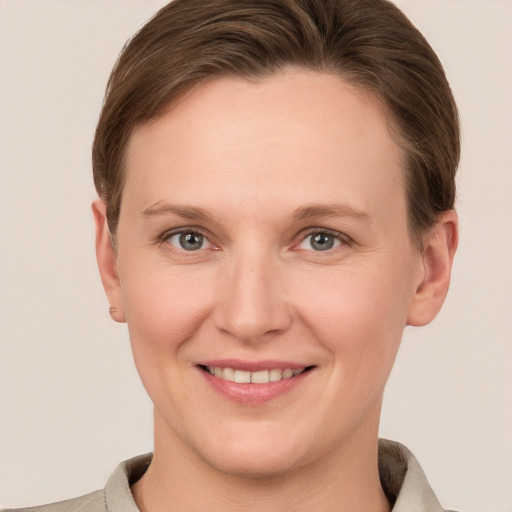 Joyful white young-adult female with short  brown hair and grey eyes