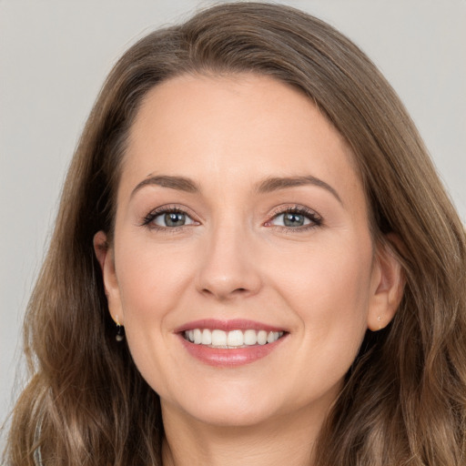 Joyful white young-adult female with long  brown hair and grey eyes