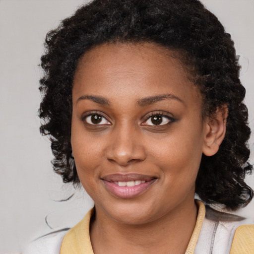 Joyful black young-adult female with long  black hair and brown eyes