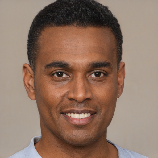 Joyful black young-adult male with short  black hair and brown eyes