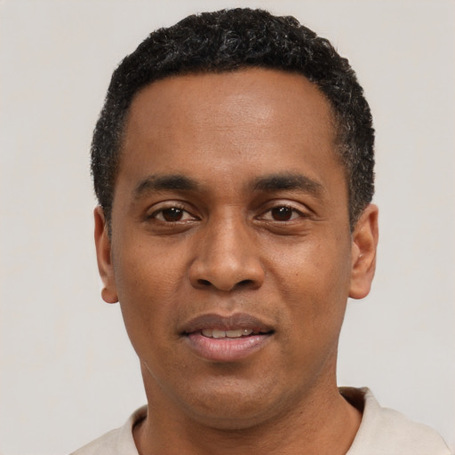 Joyful black young-adult male with short  black hair and brown eyes