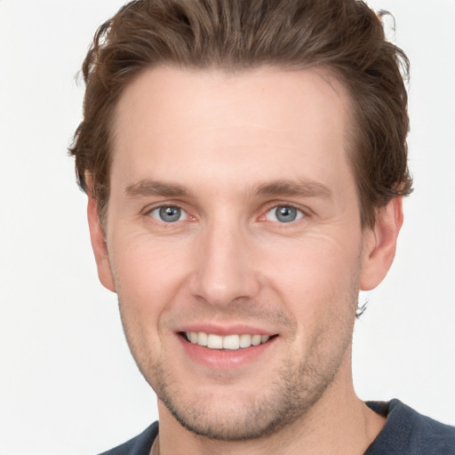 Joyful white young-adult male with short  brown hair and grey eyes