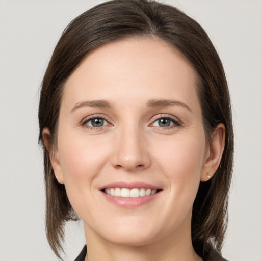 Joyful white young-adult female with medium  brown hair and grey eyes