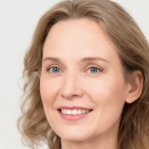 Joyful white adult female with long  brown hair and blue eyes