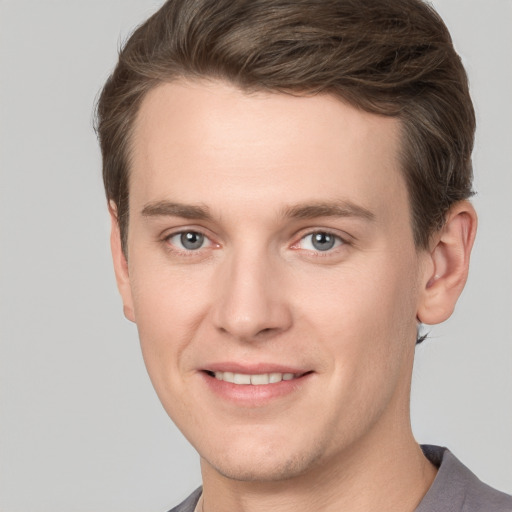 Joyful white young-adult male with short  brown hair and grey eyes