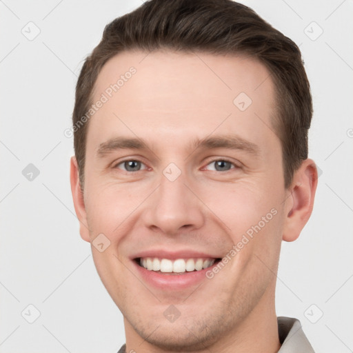 Joyful white young-adult male with short  brown hair and grey eyes