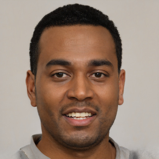 Joyful black young-adult male with short  black hair and brown eyes