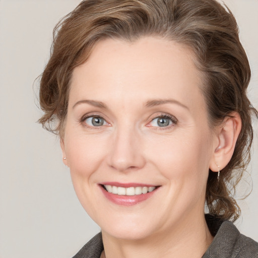 Joyful white adult female with medium  brown hair and grey eyes