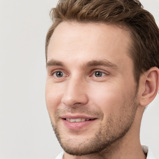 Joyful white young-adult male with short  brown hair and grey eyes