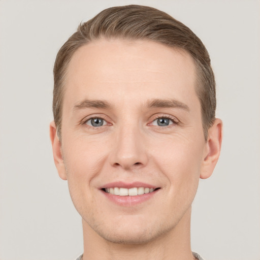 Joyful white young-adult male with short  brown hair and grey eyes