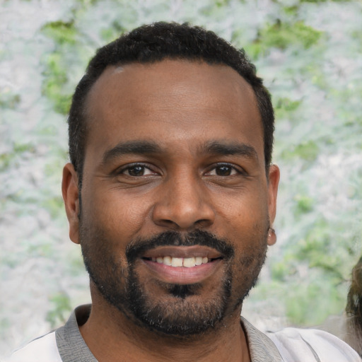 Joyful black young-adult male with short  black hair and brown eyes