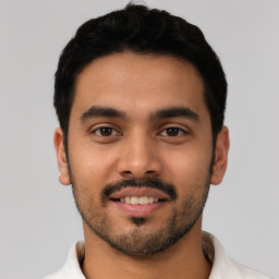 Joyful latino young-adult male with short  black hair and brown eyes