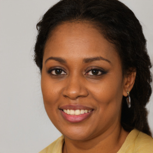 Joyful black young-adult female with long  brown hair and brown eyes